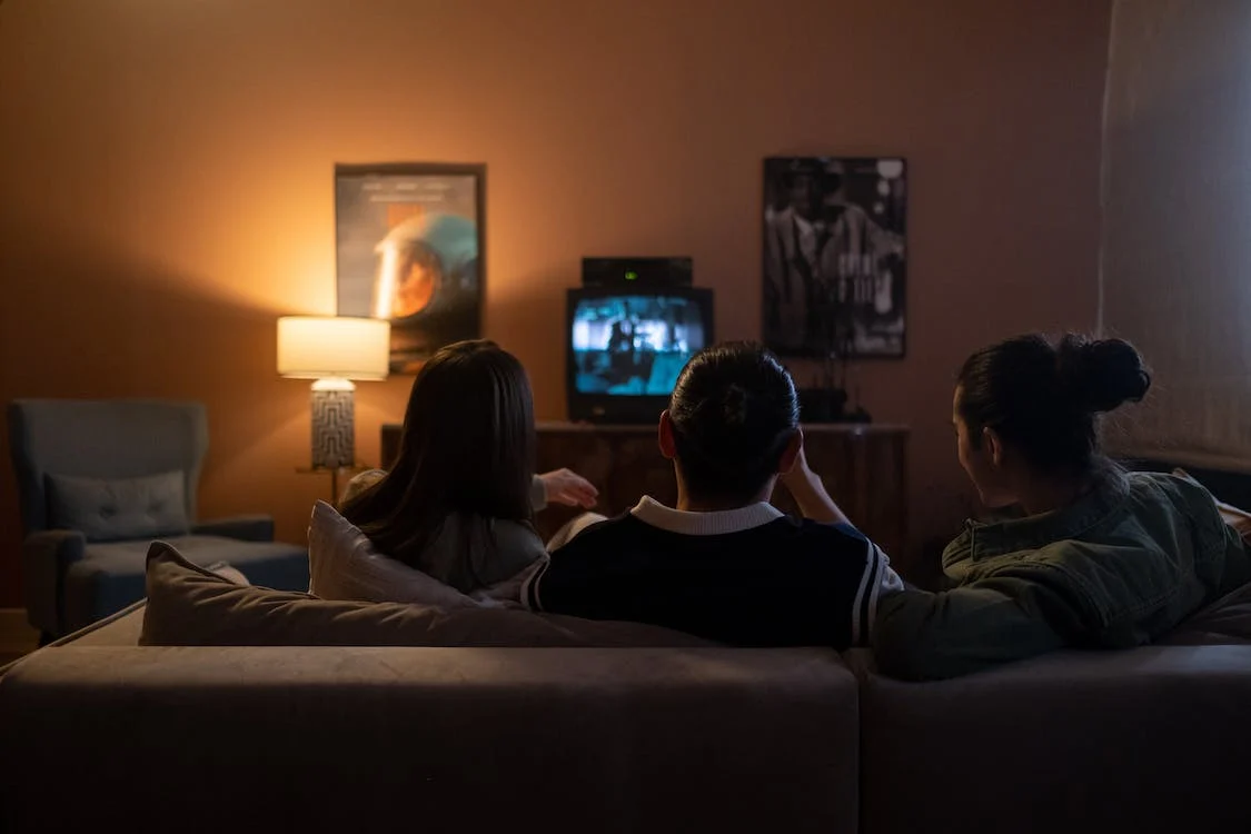 Three friends sitting on a sofa watching a movie together